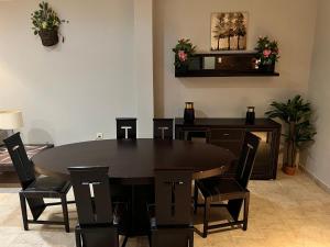 uma sala de jantar com uma mesa preta e cadeiras em Garden City 2 em Riade
