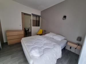 um quarto com uma cama branca e uma cadeira amarela em Coeur de Cauterets appartement 53m² 4/6 personnes em Cauterets