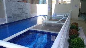 a swimming pool with a chair sitting in the middle of it at Mediterrâneo 507 - Todo Equipado, Ar Condicionado, Churrasqueira na Varanda, Internet Fibra 600MB, Estacionamento Grátis in Cabo Frio