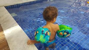 a young boy in a swimming pool with a life vest at Mediterrâneo 507 - Todo Equipado, Ar Condicionado, Churrasqueira na Varanda, Internet Fibra 600MB, Estacionamento Grátis in Cabo Frio