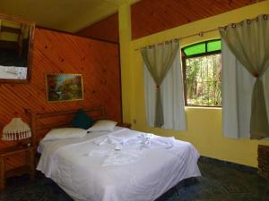 1 dormitorio con cama blanca y ventana en Pousada Santa Clara, en Visconde De Maua