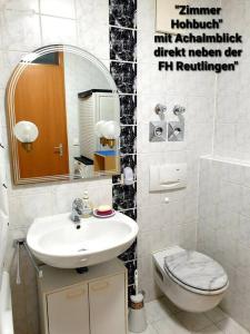 ein Badezimmer mit einem Waschbecken, einem WC und einem Spiegel in der Unterkunft Zimmer Hohbuch mit Achalmblick in Reutlingen