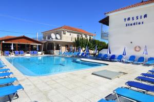 una piscina con sillas azules y un hotel en Hotel Tassia for families & couples, en Laganas