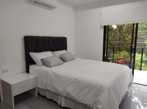 a white bedroom with a large bed and a window at Hakuna in San Juanillo