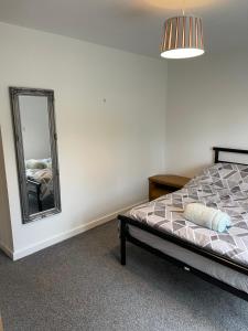 1 dormitorio con cama y espejo en Lovely 4 bed apartment in centre of Formby en Formby