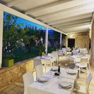 un restaurante con mesas blancas y sillas blancas en Masseria Valente, en Ostuni