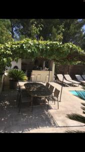 Un patio con una mesa y sillas bajo una sombrilla. en Villa piscine 6km de Cassis 12 couchages, en Roquefort-la-Bédoule