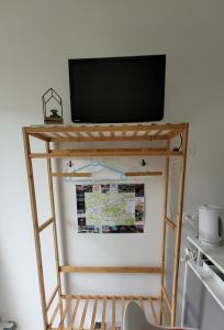 a tv on top of a stand with a shelf at Studio Cosy in Nazelles