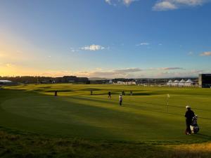 a group of people playing golf on a golf course at Ailim House Serviced Cottage Escape, around the corner from the Old Course in St Andrews