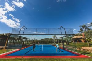 2 personnes jouant au tennis sur un court dans l'établissement Fazenda Verde - Praia do Rosa, à Praia do Rosa