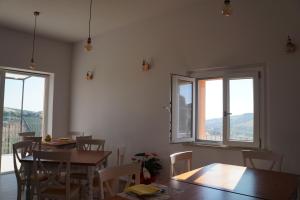 ein Esszimmer mit Tischen, Stühlen und Fenstern in der Unterkunft La Sperella Bed and Breakfast in Fermo