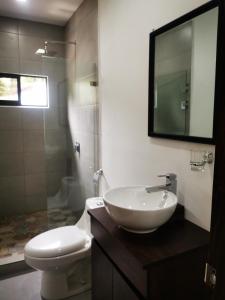 a bathroom with a sink and a toilet and a mirror at Hakuna in San Juanillo