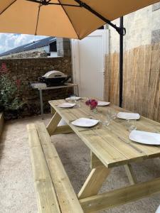 a wooden picnic table with an umbrella and glasses at CHEZ ROZ in Rostrenen