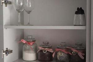 a white shelf with wine glasses and jars at Apartament Orla 47F Perłowa Dolina in Bydgoszcz