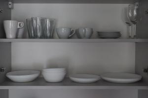 a shelf with bowls and plates and wine glasses at Apartament Orla 47F Perłowa Dolina in Bydgoszcz