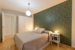 a bedroom with a bed and a green wall at Capricho en el centro de Granada. in Granada