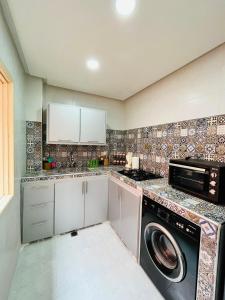 uma cozinha com máquina de lavar e secar roupa em Appartement avec jolie terrasse privée et parking Apartment with nice private terrace and parking em Marrakech