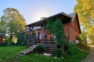 a large brick house with a porch on a yard at Agroturystyka Sòjkowy Zakątek in Dzierżążno Małe