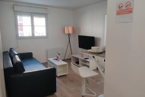 een woonkamer met een bank en een bureau met een televisie bij Appart Cosy Auber Porte de Paris in Aubervilliers