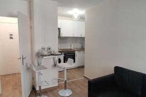 a kitchen with white cabinets and a table and chairs at Appart Cosy Auber Porte de Paris in Aubervilliers