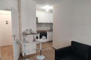 cocina con armarios blancos, mesa y sillas en Appart Cosy Auber Porte de Paris, en Aubervilliers