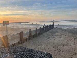 a wooden fence on a beach with people in the water at Jolly Sailors Retreat in Wells next the Sea