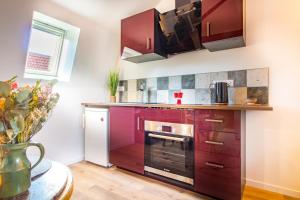 a kitchen with red cabinets and a stove at Jacuzzi® - La petite Romantique - FloBNB in Laon