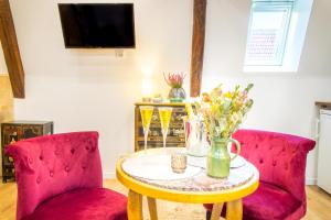 - un salon avec deux chaises rouges et une table fleurie dans l'établissement Jacuzzi® - La petite Romantique - FloBNB, à Laon