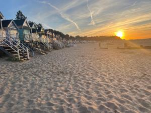 a row of beach huts on the beach at sunset at Jolly Sailors Retreat in Wells next the Sea