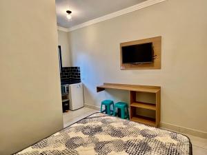 Cet appartement comprend une chambre avec un lit et une petite cuisine. dans l'établissement Marmeu Tombo com Hidro Aquecida Privativa, à Guarujá