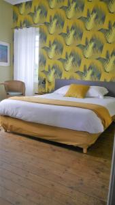 a bedroom with a large bed with a yellow wall at Maison Castel Braz in Pont-Aven