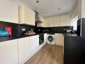 a kitchen with white cabinets and a washer and dryer at Spacious and stylish 3-bed home ideal for families in Stockton-on-Tees