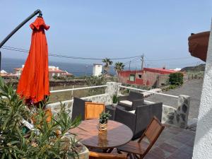 un patio con sombrilla naranja, mesa y sillas en La Casita de la Breña., en La Frontera