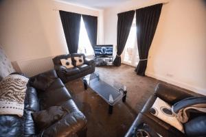 a living room with a leather couch and a television at Beautiful Sea View, Whitburn, South Tyneside 