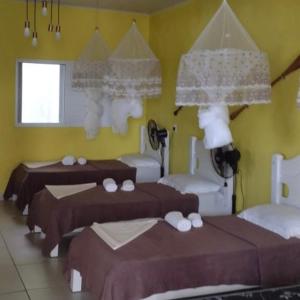ein Schlafzimmer mit 3 Betten und einer gelben Wand in der Unterkunft POUSADA CHARMOSA in Superagui