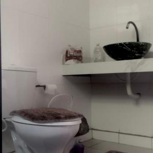 a bathroom with a white toilet and a sink at POUSADA CHARMOSA in Superagui