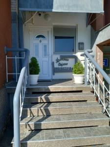 a stairway leading to a white door with potted plants at Apartman Dejana in Apatin