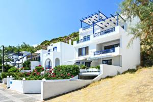 un edificio blanco con flores delante en Aliki Studios en Paralia Agias Foteinis