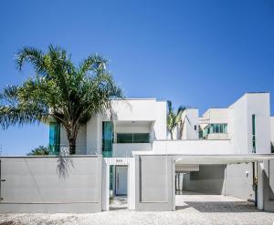 una casa blanca con una palmera delante de ella en Casa de Praia alto Padrao, en Balneário Camboriú