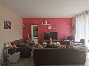a living room with a couch and a red wall at Villa individuelle 5 mn Lille centre Chr/eurasante in Haubourdin