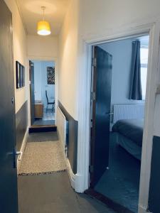 un couloir avec une porte s'ouvrant sur une chambre avec un lit dans l'établissement F1 16 Glanmor Cres, à Swansea