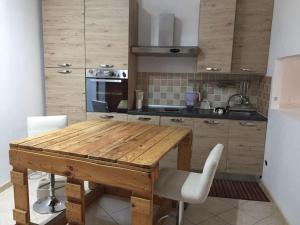 cocina con mesa de madera y sillas blancas en GIARDINI VERDI Intero appartamento, en Muravera