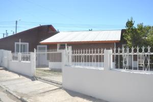 una cerca blanca frente a una casa en Departamentos Lizkar en Esquel