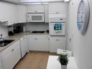 a white kitchen with white cabinets and a sink at Tide Hollywood in Hollywood