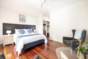a bedroom with a bed and a chair and a table at Camelot Boutique Accommodation in Mount Tamborine