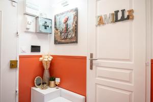 Paris Homestay of Happyness في لو كرملين-بيستر: حمام برتقالي وبيض مع باب أبيض