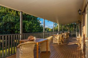 a deck with a wooden table and chairs on it at Camelot Boutique Accommodation in Mount Tamborine