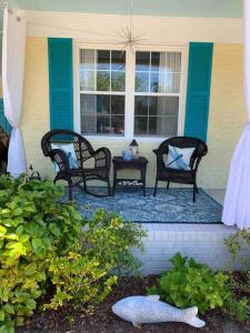 une véranda avec trois chaises, une table et une fenêtre dans l'établissement Downtown- Sunshine Cottage and Golf Cart, à Southport