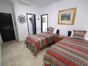 Habitación de hotel con 2 camas y espejo en Casa Dahlia, en Mazatlán