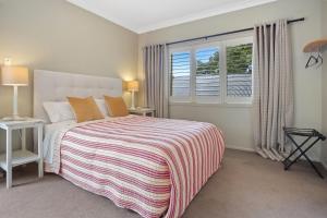 een slaapkamer met een bed met een gestreepte deken en een raam bij Titoki Cottage in Tahawai